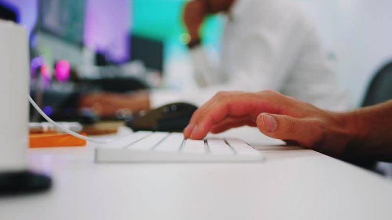 Une main sur un clavier d'ordinateur blanc.